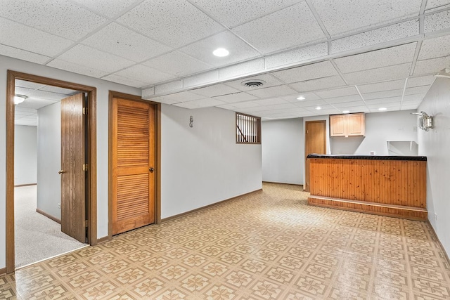 basement featuring bar area and a drop ceiling