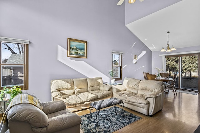 living room featuring dark hardwood / wood-style floors, ceiling fan with notable chandelier, and high vaulted ceiling