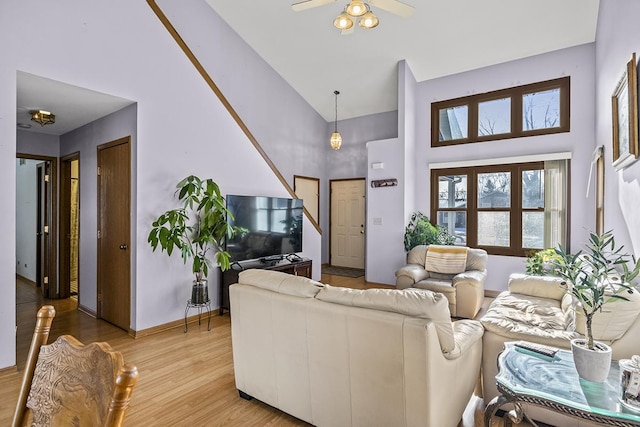 living room featuring a towering ceiling, ceiling fan, and light hardwood / wood-style flooring