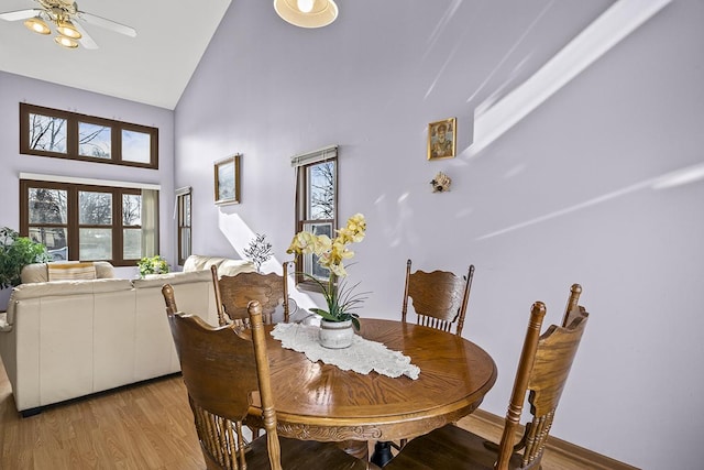 dining space with ceiling fan, high vaulted ceiling, and light hardwood / wood-style floors