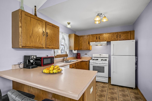 kitchen featuring white appliances, a breakfast bar, kitchen peninsula, and sink