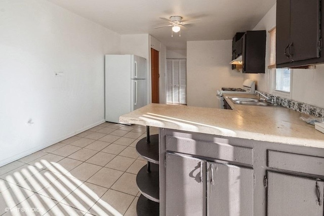 kitchen with kitchen peninsula, sink, white refrigerator, stove, and light tile patterned flooring