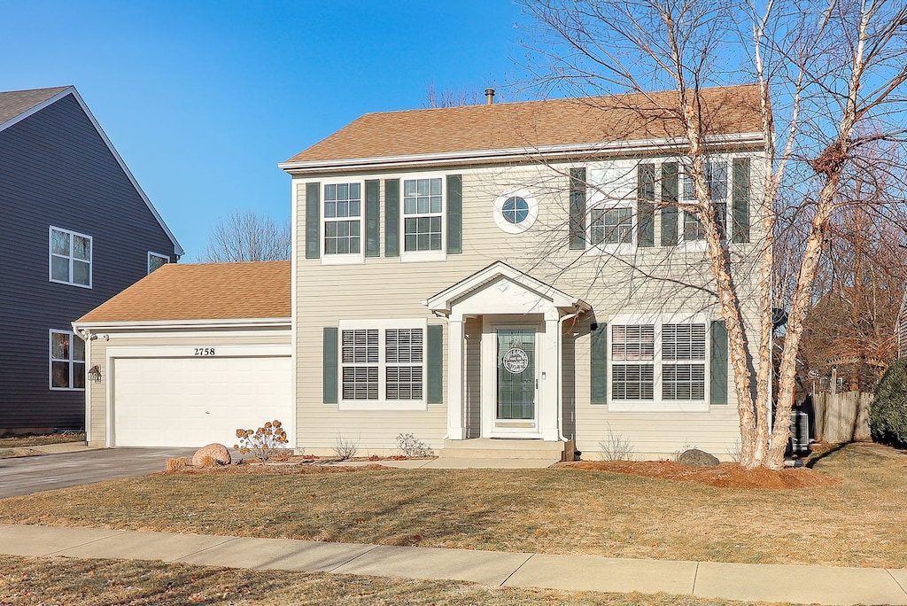 colonial home featuring a garage and a front yard