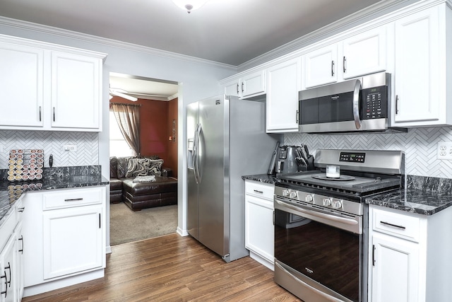 kitchen with crown molding, appliances with stainless steel finishes, backsplash, white cabinets, and dark stone counters