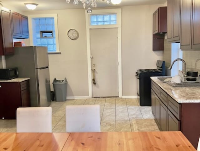 kitchen with dark brown cabinets, gas stove, decorative backsplash, and light tile patterned flooring