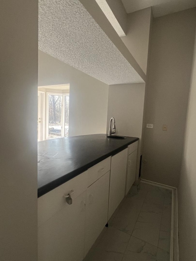 kitchen with white cabinetry, sink, and a textured ceiling