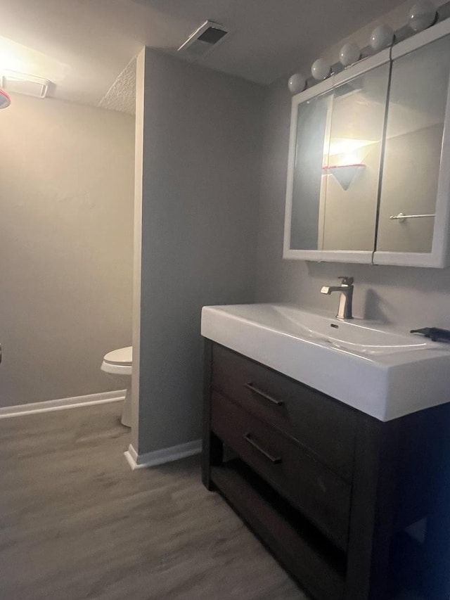 bathroom with hardwood / wood-style flooring, vanity, and toilet