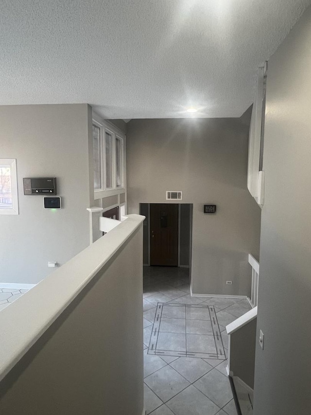 corridor featuring a textured ceiling and light tile patterned floors