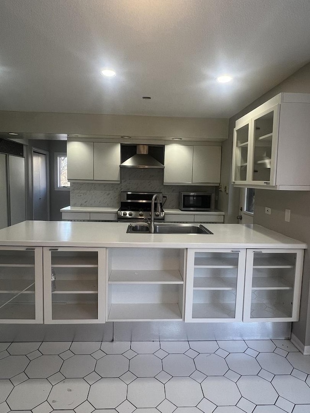 kitchen featuring sink, stainless steel appliances, tasteful backsplash, white cabinets, and wall chimney exhaust hood