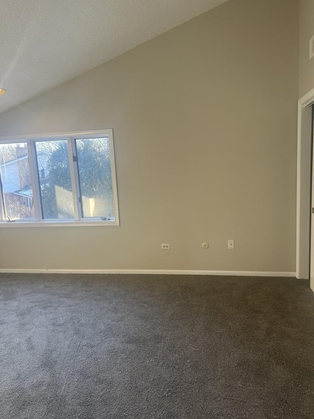 empty room featuring vaulted ceiling, a textured ceiling, and dark colored carpet