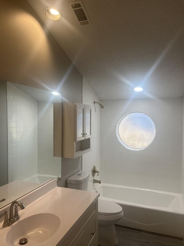 full bathroom featuring wood-type flooring, vanity,  shower combination, toilet, and a textured ceiling