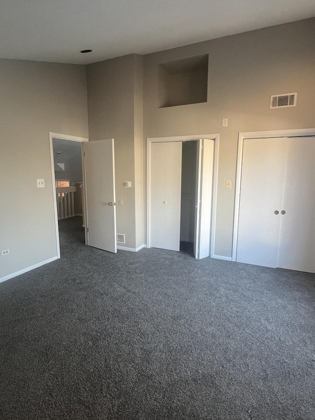 unfurnished bedroom with dark carpet and a high ceiling