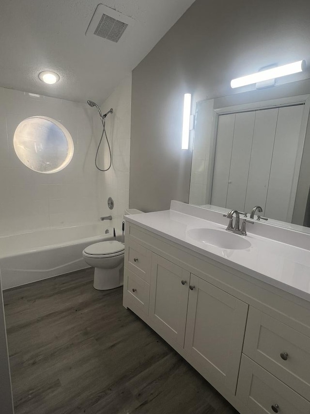 full bathroom with bathing tub / shower combination, hardwood / wood-style floors, vanity, a textured ceiling, and toilet