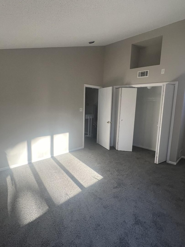 unfurnished bedroom with a towering ceiling, a textured ceiling, and carpet flooring