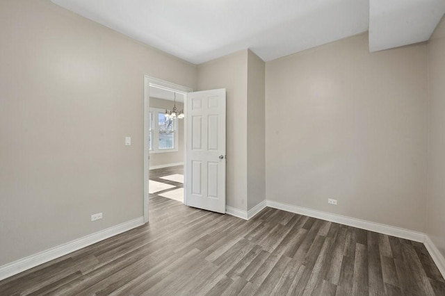 unfurnished room featuring wood-type flooring and an inviting chandelier