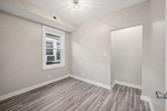 empty room with hardwood / wood-style flooring and a chandelier