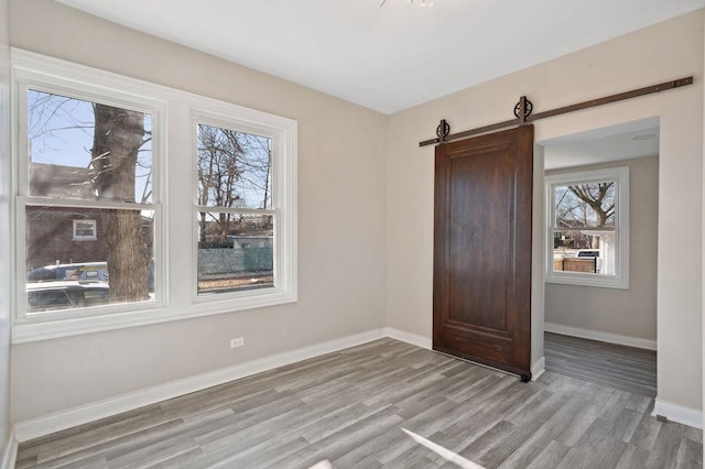 unfurnished bedroom featuring a barn door and light hardwood / wood-style floors