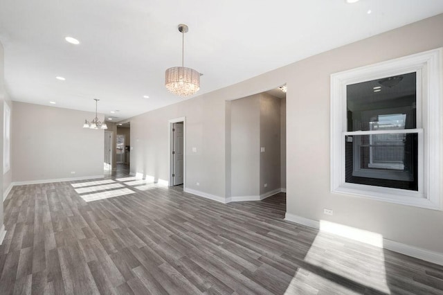 unfurnished living room featuring an inviting chandelier and dark wood-type flooring