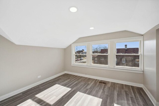 additional living space with plenty of natural light, dark hardwood / wood-style flooring, and lofted ceiling