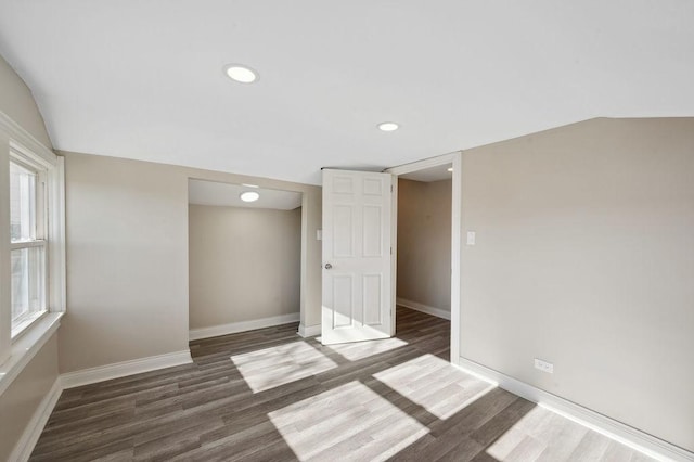 spare room featuring dark hardwood / wood-style floors, vaulted ceiling, and a wealth of natural light