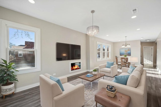 living room featuring a notable chandelier, a wealth of natural light, and dark hardwood / wood-style flooring