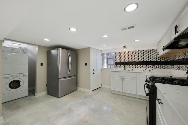 kitchen with white cabinetry, stacked washer and dryer, gas stove, and stainless steel refrigerator