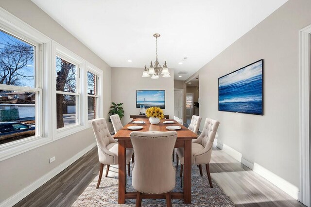 dining space featuring hardwood / wood-style flooring and an inviting chandelier