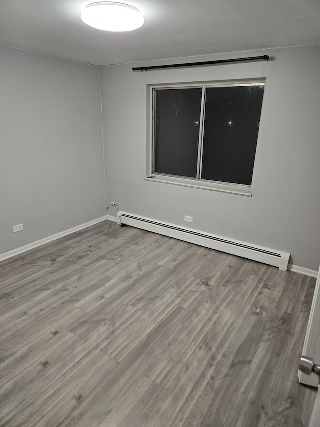 unfurnished room featuring a baseboard radiator and light wood-type flooring