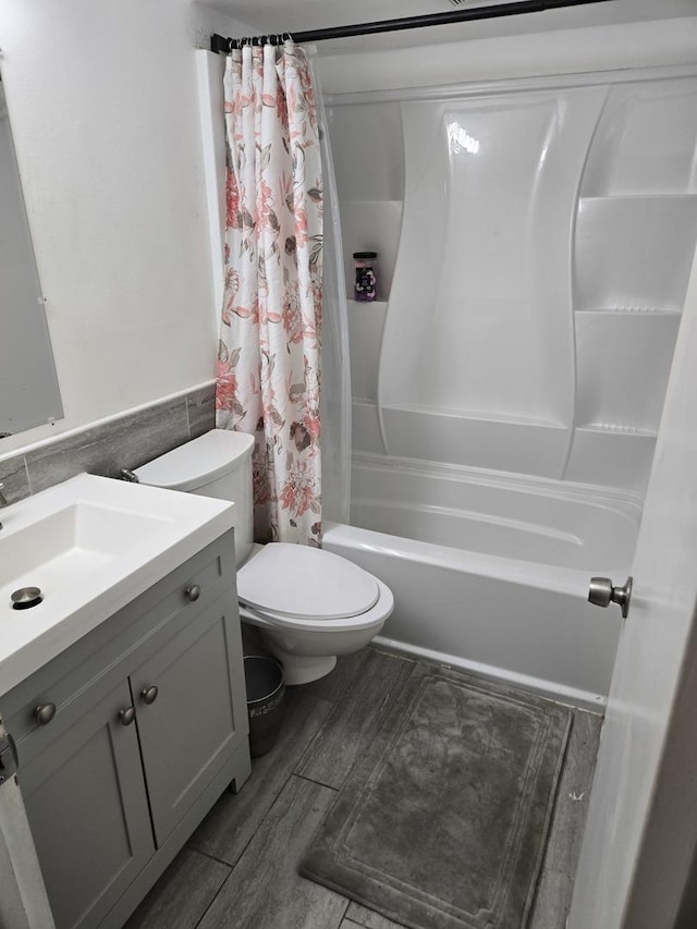 full bathroom featuring tile walls, hardwood / wood-style flooring, vanity, toilet, and shower / bath combo with shower curtain