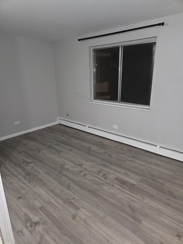 spare room featuring a baseboard heating unit and hardwood / wood-style floors