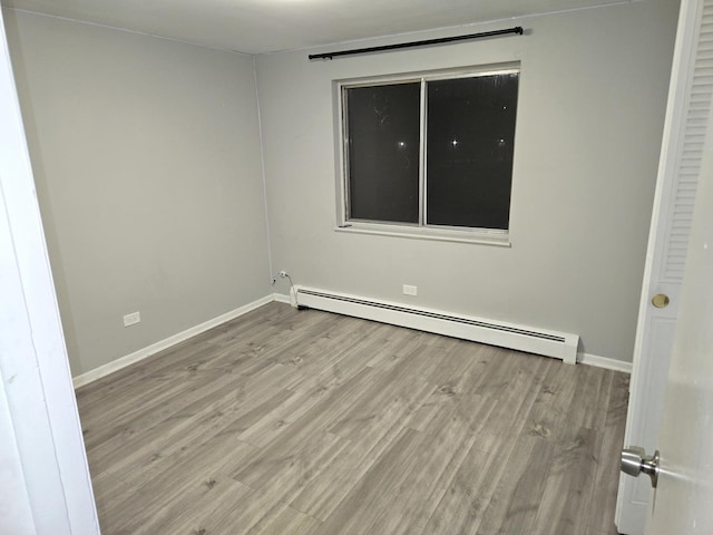 spare room with a baseboard heating unit and light wood-type flooring