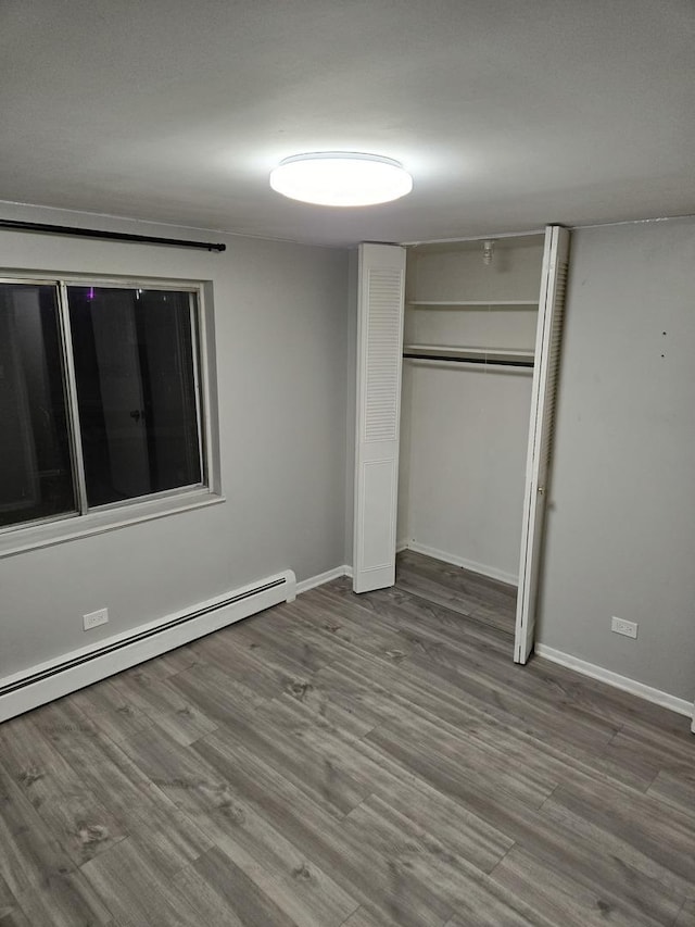 unfurnished bedroom with a baseboard radiator, hardwood / wood-style floors, and a closet