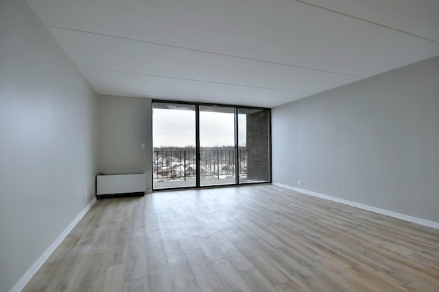 empty room featuring a wall of windows and light wood-type flooring