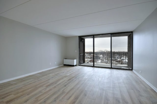 spare room with light hardwood / wood-style flooring and floor to ceiling windows