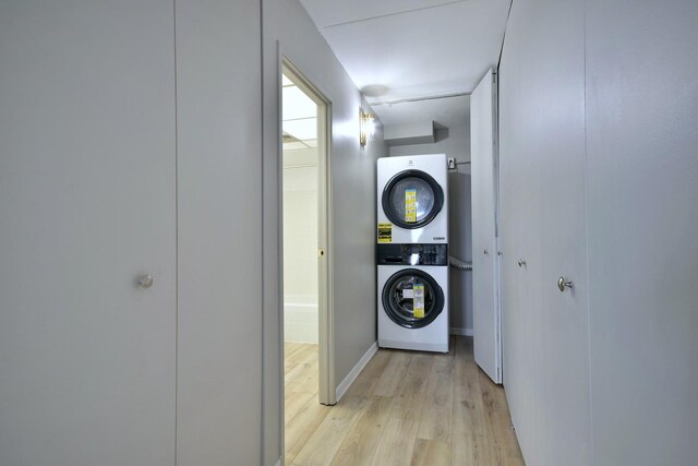 clothes washing area featuring stacked washer / drying machine and light hardwood / wood-style flooring