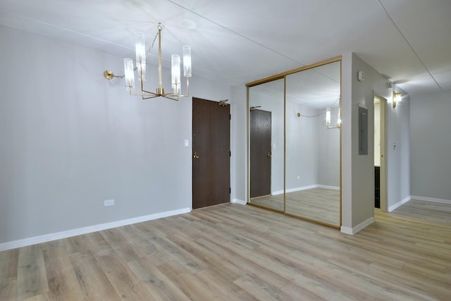 interior space with a chandelier, electric panel, and light hardwood / wood-style flooring