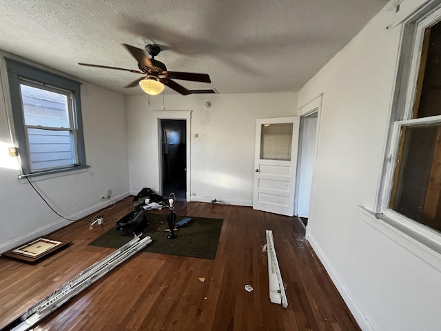 workout room with dark wood-type flooring, ceiling fan, and a textured ceiling