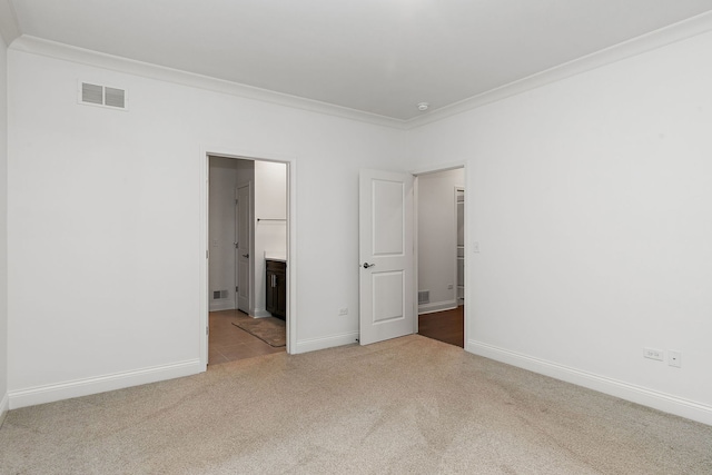 unfurnished bedroom featuring light carpet, ensuite bath, and ornamental molding