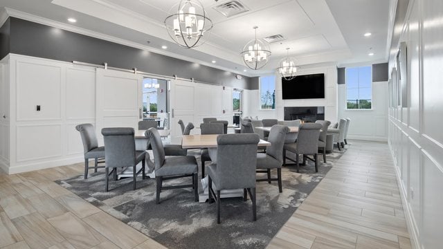 dining space featuring crown molding, a raised ceiling, a barn door, a notable chandelier, and a large fireplace