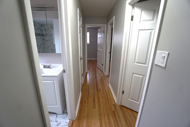 hall with light hardwood / wood-style floors and sink