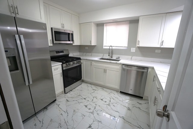 kitchen with sink, light stone counters, white cabinets, and appliances with stainless steel finishes