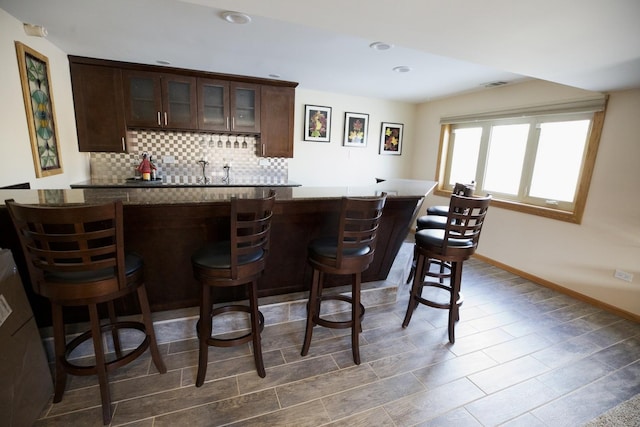 bar featuring tasteful backsplash and dark brown cabinets