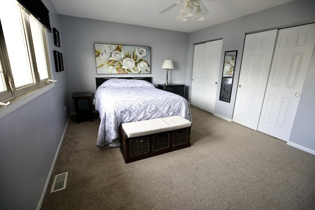 bedroom featuring two closets, ceiling fan, and carpet