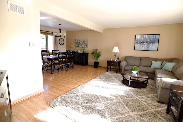 living room featuring beamed ceiling, a notable chandelier, and hardwood / wood-style flooring