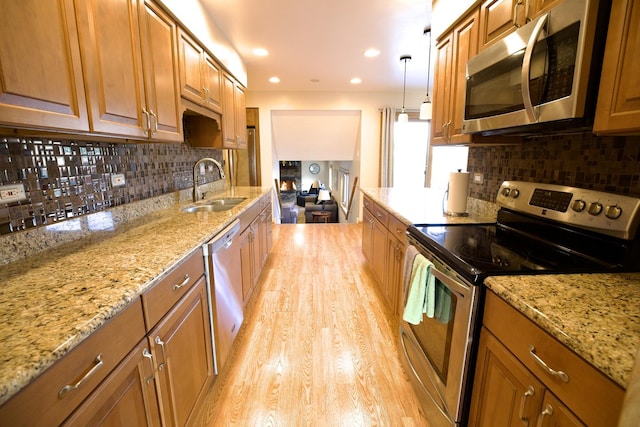 kitchen featuring light stone countertops, appliances with stainless steel finishes, sink, and pendant lighting