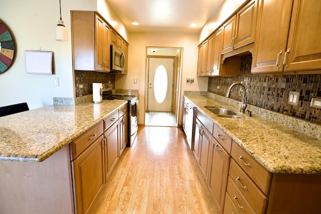 kitchen with appliances with stainless steel finishes, light stone countertops, sink, and hanging light fixtures