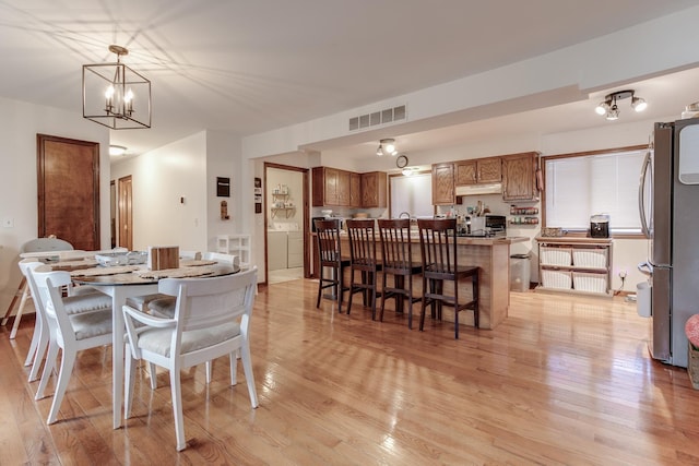 dining space featuring a notable chandelier, light hardwood / wood-style flooring, and washer / clothes dryer