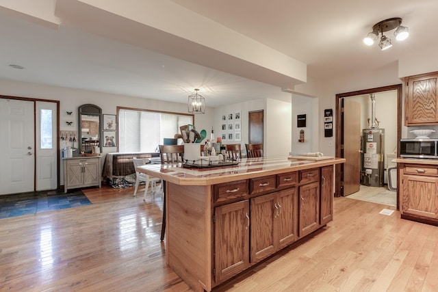 kitchen with light hardwood / wood-style floors, hanging light fixtures, gas water heater, and a kitchen island