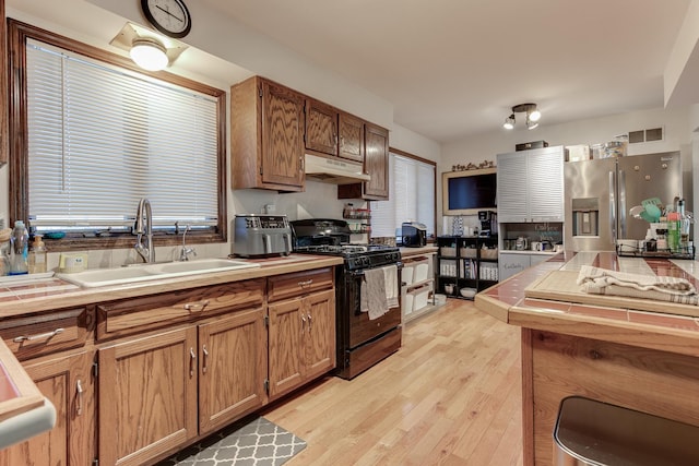 kitchen featuring sink, stainless steel fridge with ice dispenser, black range with gas stovetop, and light hardwood / wood-style flooring