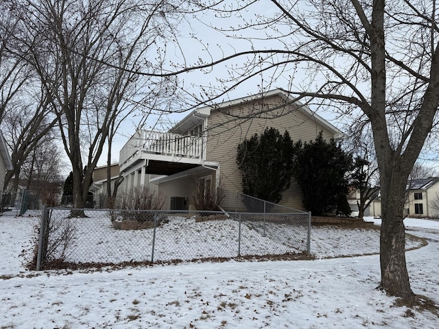 snow covered house featuring a balcony